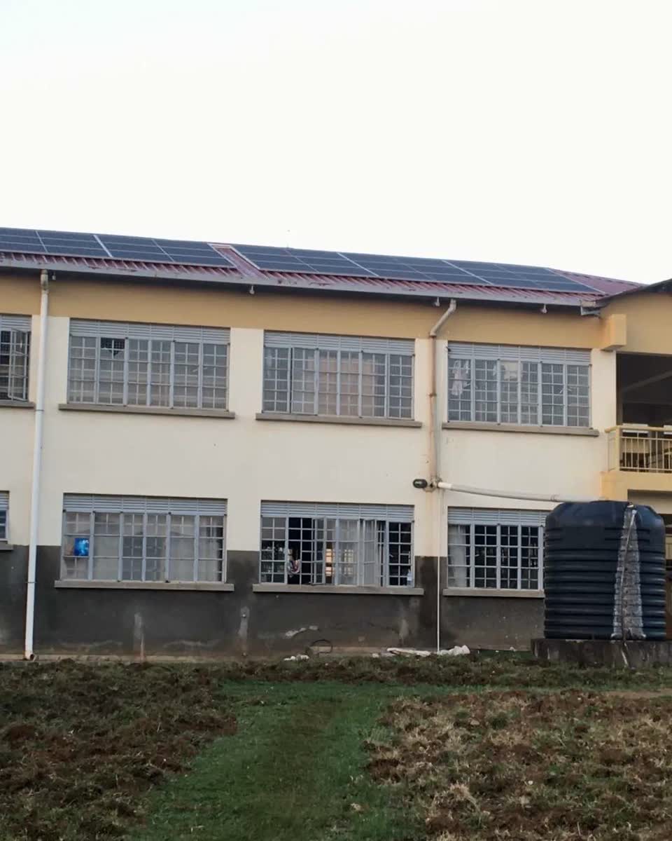 A two storey institutional building at dusk with solar panels covering its roof.