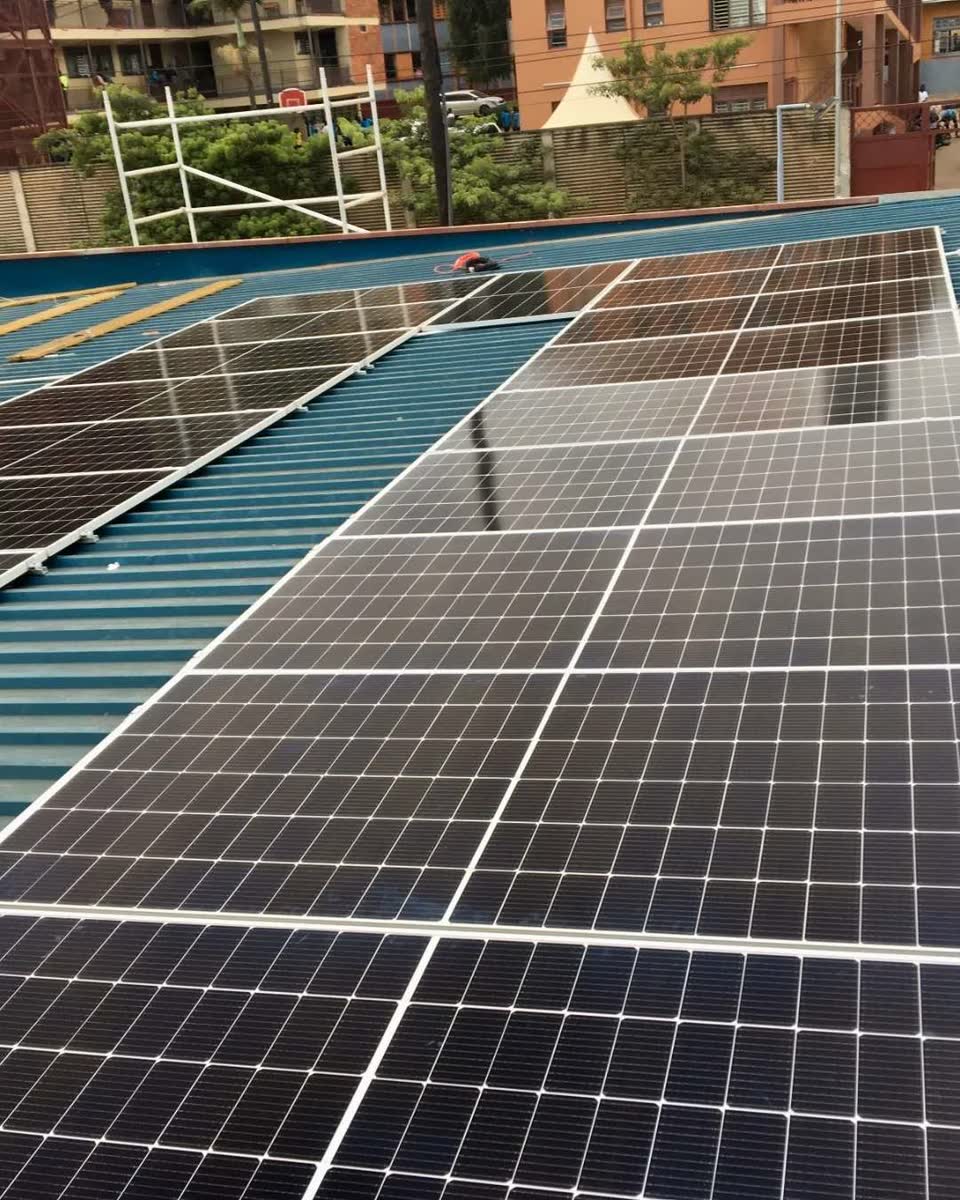 A tilted solar array on a blue metal roof, racking rails visible between the rows.